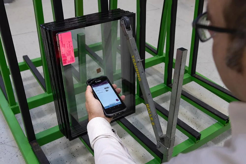 Worker scanning a barcode label on an insulating glass unit for end-to-end traceability